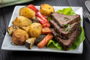 beef roasted in fresh herbs surrounded by baked vegetables