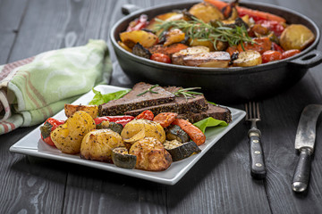 beef roasted in fresh herbs surrounded by baked vegetables