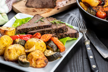 beef roasted in fresh herbs surrounded by baked vegetables