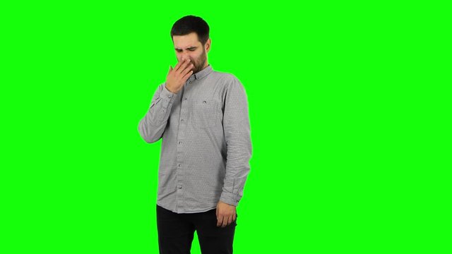Brunette guy is showing disgust for bad smell or taste. Green screen