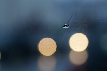 Wet glass background with raindrops and blurry background with bokeh. Blue green tint color.