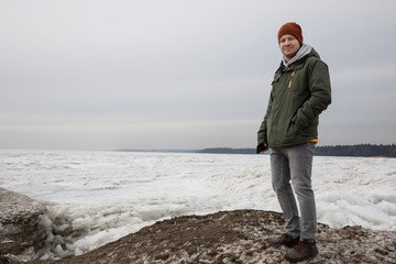 portrait of a man on a lake in winter. The guy in the hat and jacket against the ice