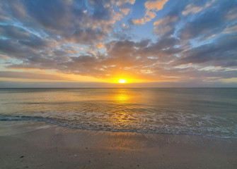 Fototapeta premium Abstract seascape panoramic background - Orange color in the sky, sunset late afternoon. Calm seas/ocean in the bottom of the frame. Minimalistic simple background image, blue and yellow colors.