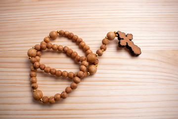 wooden rosy with a cross rests on a wooden table