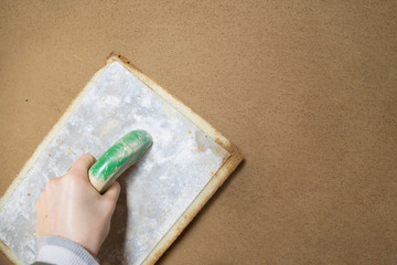 Closeup of a plasterer finishing a wall made of clay plaster with a sponge board