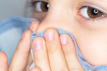 Close-up of young girl blowing her nose