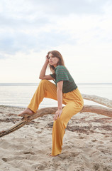 beautiful fashionable girl on the beach dressed in a green sweatshirt and yellow pants, stylish retro clothing, lifestyle and fashion