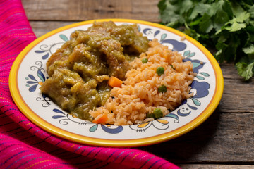 Mexican pork chicharron with green sauce and rice on wooden background