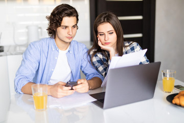 Young couple managing home accounts in kitchen, trying to save some money by cutting family expenses. Finances, bankruptcy, taxes, money, accounting and financial problems concept