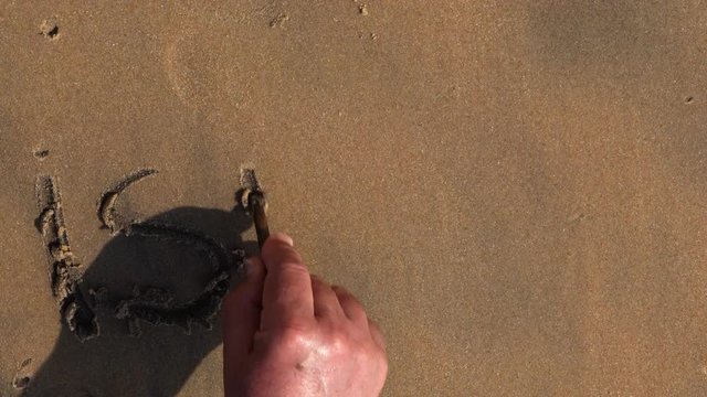 Male hand writes Israel on the sea sand