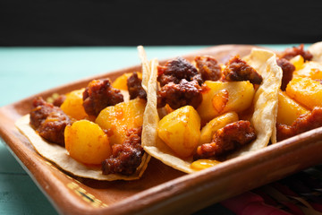 Mexican chorizo with potatoes tacos on turquoise background