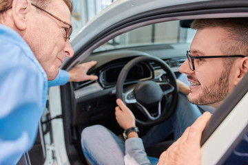 Test drive. Sales manager showing customers interior of a new car model