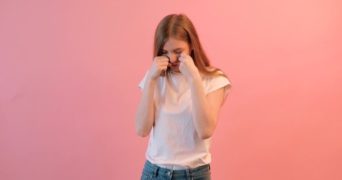 beautiful girl upset woman crying on a pink background, in a bad mood
