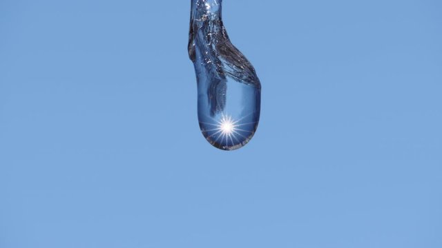 Incredible macro slow motion shot of water dripping from end of thawing icicle melting in spring with sunlight reflected inside. Looping possible.