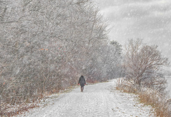 Woman practices social distancing on snowy path in the woods