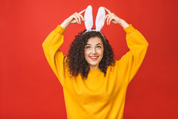Young caucasian woman wearing cute easter rabbit ears over red isolated background while smiling...