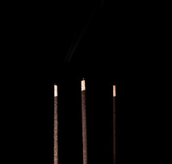 Indian incense sticks. Burning, brown incense sticks on a dark background. Smoke with aroma rises....