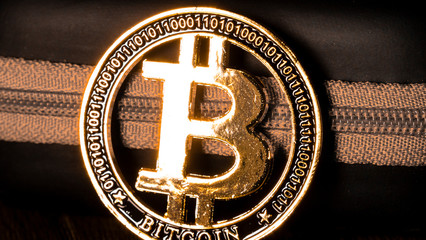 Bitcoin coin, BTC. Bitcoin gold coin with program code next to the zipper, close-up. Symbol of...