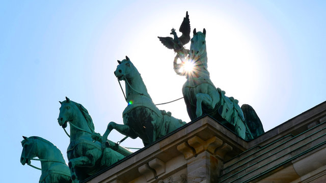 Brandenburg Gate against the sun. Close up. Major landmark and national symbol of Berlin, Germany. Statue of the Goddess Victoria with Horses on Brandenburg Tor. Viewed from the Pariser Platz. 