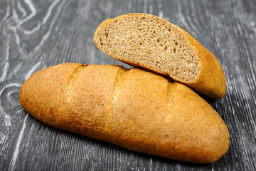Bread loaf of wheat flour with bran on a gray wooden background. For a healthy diet.
