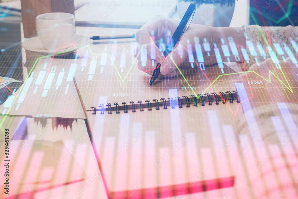 Poster Hand taking notes in notepad. Forex chart holograms in front. Concept of research. Double exposure