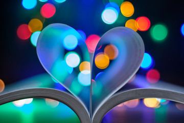 Leaves of a book shaped as a heart with lights background. Concept: love for books, love for reading