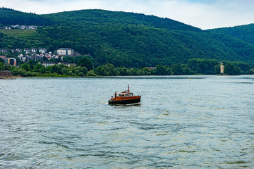 Germany, Rhine Romantic Cruise, a small boat in a body of water with a mountain in the background