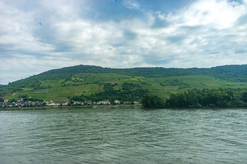 Fototapeta premium Germany, Rhine Romantic Cruise, a body of water with a mountain in the background