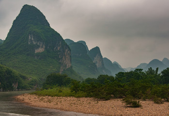 Guilin, China - May 10, 2010: Along Li River. Landscape of forested karst mountain range under...