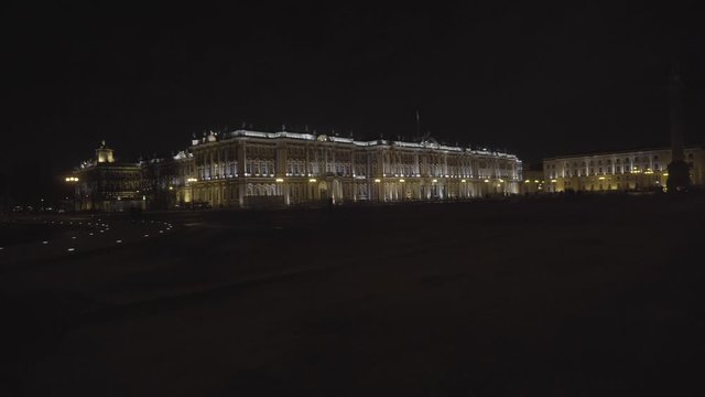 Night view of scenic illuminated architecture of Saint Petersburg city center, majestic Winter Palace with people walking around. Motion. Famous Hermitage buildin on black sky background.