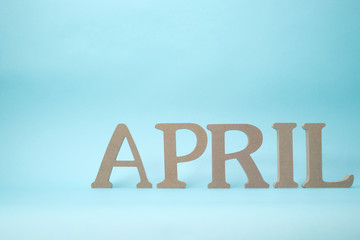水色背景の「APRIL」の木製のアルファベットのブロック 02