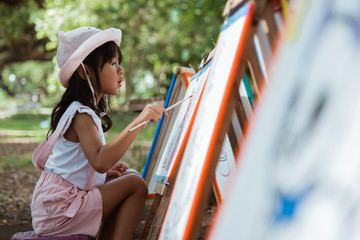 little girl drawing while on vacation in the park