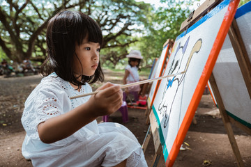 asian little girl drawing while on vacation in the garden