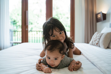 Fototapeta premium two children lie in bed while playing together in the bedroom