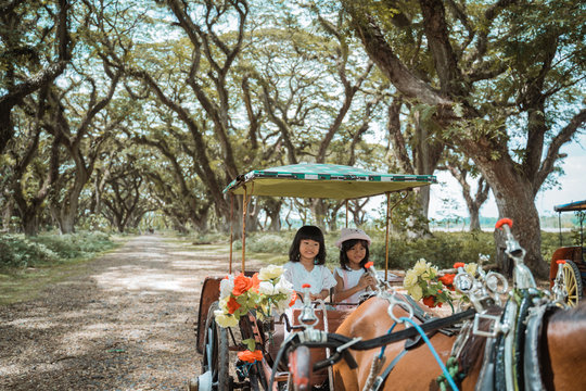 two children sit in the dokar while enjoying a vacation in the park