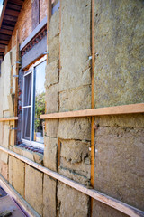 warming the walls of a stone house with a stone wool heater. Ecological insulation of rooms with building a house. Installation of cellulose thermal insulation in the wall of the frame house