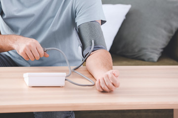 Young man measuring his blood pressure at home