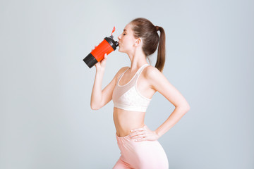 Sporty young woman with protein shake on light background - obrazy, fototapety, plakaty