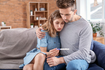 Sad young couple with pregnancy test at home