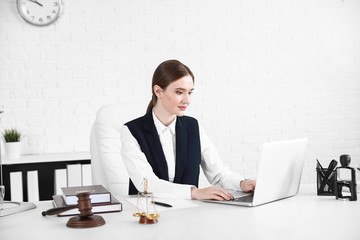 Female lawyer with laptop sitting at workplace in office