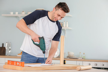 Young man assembling furniture at home