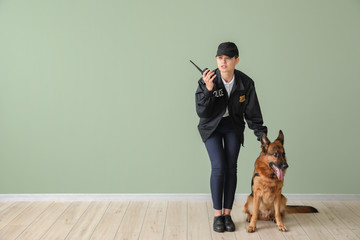 Female police officer with dog near color wall