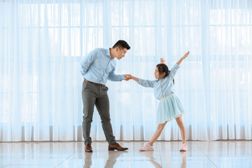 Fototapeta na wymiar Happy Asian man dancing with his little daughter at home