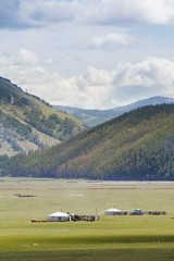 Yurt camp in the steppe, grasslands and mountains under sunny spell