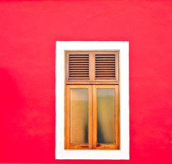 One simple wooden window in a red wall.