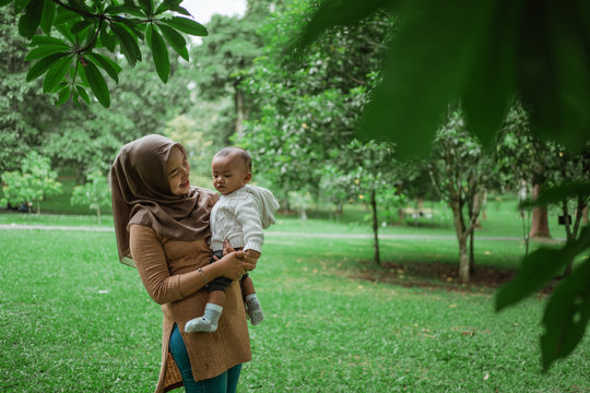 hijab woman holding little baby when enjoy vacation in the park