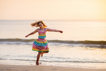 Child playing on ocean beach. Kid at sunset sea.