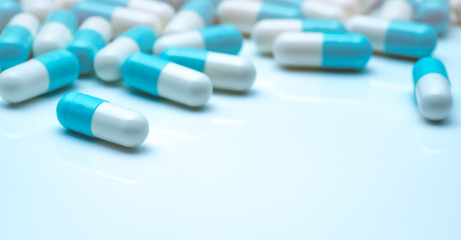 Selective focus on blue-white capsule pills. Capsule pills sperad on white background....