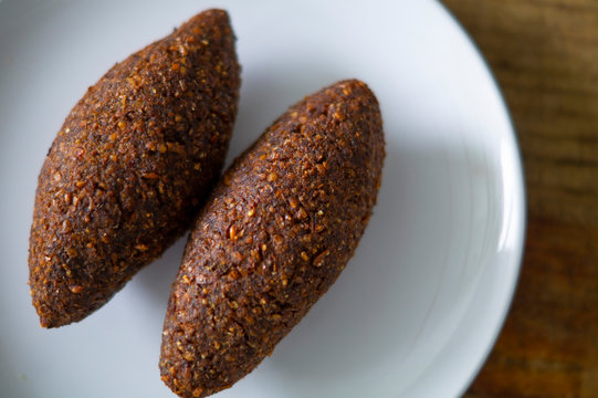 quipe, delicioso kibbeh frito con salsa de yogur en un bol servido en un plato de arcilla sobre una vieja mesa de madera oscura, receta cl&aacute;sica, vista desde arriba, espacio para copiar
