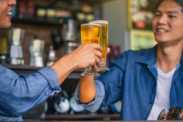 Happy friends drinking and toasting beer at brewery bar restaurant. Friendship concept with young people having fun together at cool vintage restaurant.